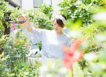 女性が花に水やりをしているイメージ写真